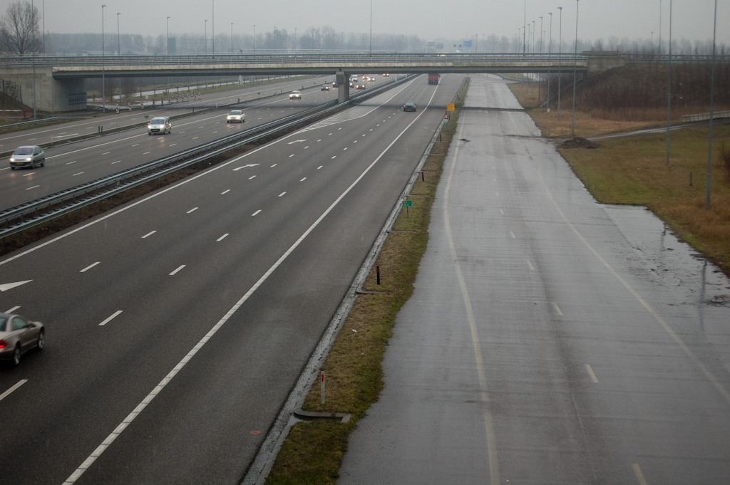 20100123-165611.jpg - Maar misschien kan de toekomstige zuidelijke rangeerbaan in de A9 hier een verlichtende rol spelen door er (een deel van) het verkeer over te leiden. De enigzins versleten markering suggereert dat die rangeerbaan al eerder in verkeer is geweest. Uiterst rechts een nog doodlopende asfaltstrook die lijkt te zijn voorbereid op aansluiting op de te realiseren klaverlus in de relatie Haarlem-Zaandam.