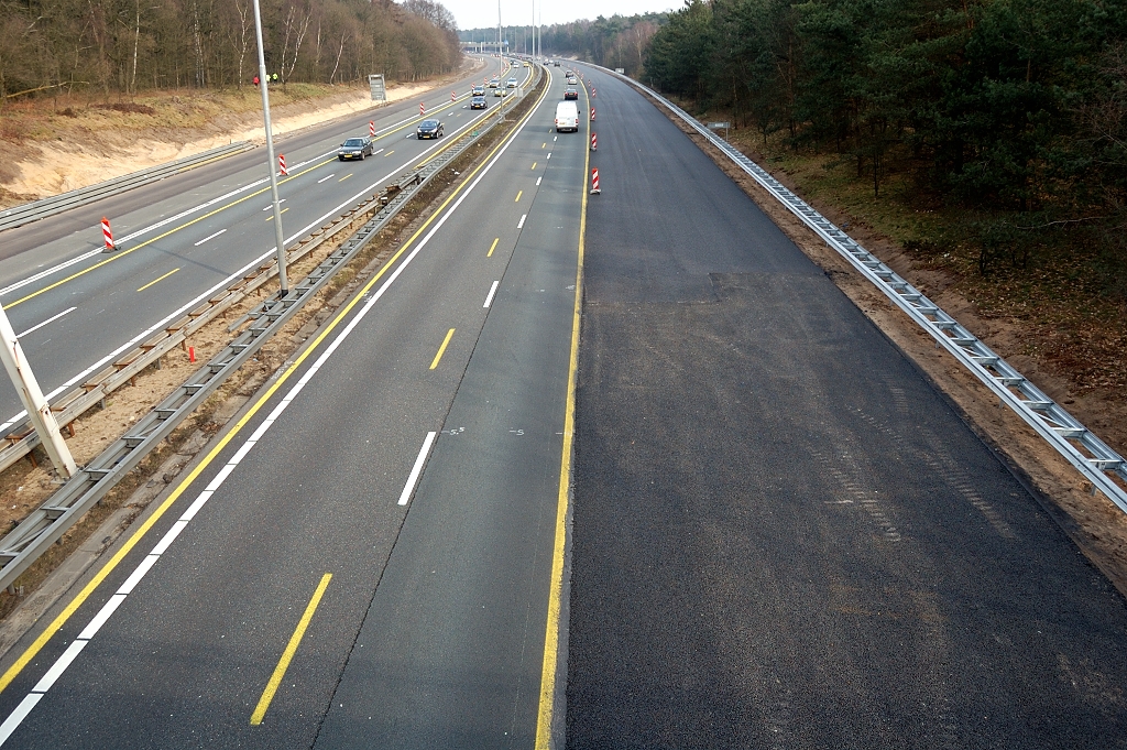 20110220-132746.JPG - 700 meter lang wegvak tussen spoorviaduct en het viaduct in de Wolfhezerweg (N783) met overal de extra verhardingsbreedte gerealiseerd, zij het nog zonder ZOAB in de HRL (links). Tevens doorlopend nieuwe geleiderail in de rechter buitenberm. Voorheen hadden we hier obstakelvrije bermen zonder geleiderail. Misschien is het zo uitgevoerd om bomen te sparen.