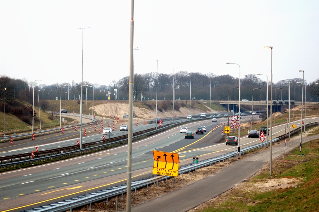 20110220-155137.JPG - Aan de zuidzijde van de aansluiting Renkum zijn reeds 2x3 rijstroken in verkeer. Foto genomen vanaf de stuwwal direct ten noorden van de uiterwaarden van de Nederrijn. die in de jaren 70 werd voorzien van een ingraving om er RW50 doorheen te leiden. Ook de aansluiting lijkt in zijn geheel in het landschap te zijn ontgraven, waardoor de weggebruiker op de N225 de rijksweg als niveau -1 ervaart.