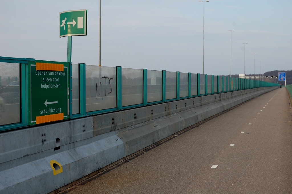 20110220-161626.JPG - Stalen barrier op de Nederrijnbrug ziet er al jaren oud uit. De buitenste rijstroken hebben immers al een geschiedenis achter zich van weef- of spitssttrook, waarbij telkens de vluchtstrook is opgegeven. Bij de vluchtwegen zien we minder verweerd metaal, maar niet zo nieuw dat het in het huidige project zou zijn gemonteerd. Moet dus wel van de spitsstrook aanleg zijn.