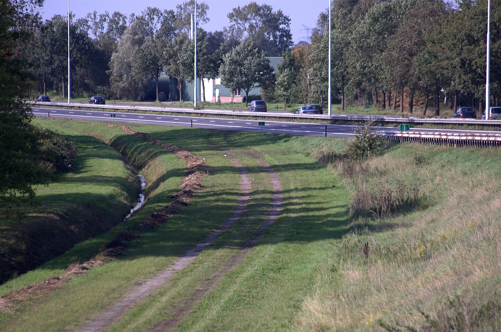 20101003-150110.bmp - Karrespoor vanaf de A58 op het nog duidelijk te herkennen tracé van de voormalige afrit vanuit de richting Tilburg. In dit geval lag het divergentiepunt vóór de helling naar de brug over het Wilhelminakanaal, zodat de gehele afrit zich op maaiveldhoogte bevond.