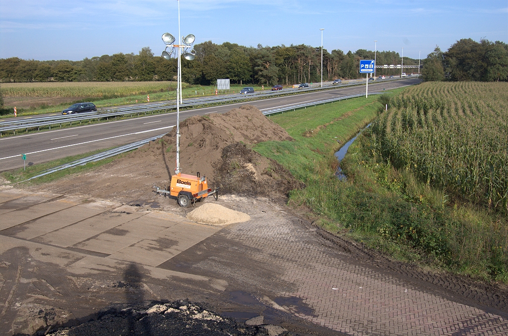 20101003-164802.bmp - Na buitengebruikstelling van de militaire aansluiting (jaartal onbekend) werd er een aarden wal opgeworpen over de af- en toerit, parallel aan de A58. Die is nu verwijderd, maar voor werkverkeerdoeleinden heeft men de kortste weg gekozen met rijplaten loodrecht op de vluchtstrook. Kromming in de toerit nog net zichtbaar, maar we weten dus niet in hoeverre de klinkerverharding nog aanwezig is onder het gras en aansluit op de autosnelweg.