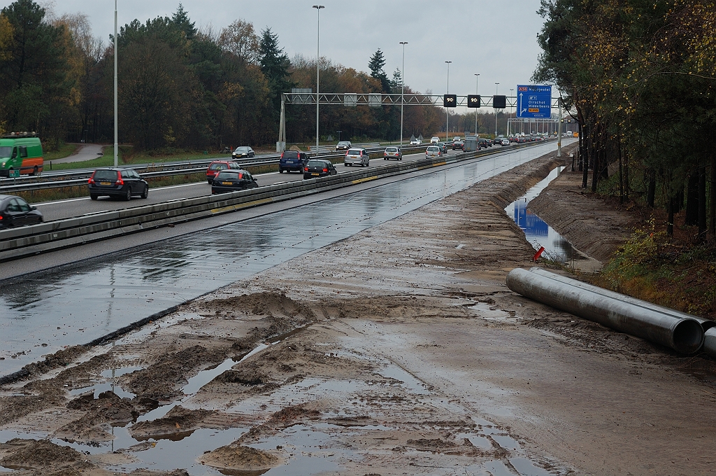 20101114-144041.JPG - En hoe gaat het nu verder met dit autosnelwegmonument? Het antwoord wordt gegeven door de bermslootgravers. De nieuwe watergang buigt mee met de oude toerit in de richting Tilburg, en sluit aan op de bestaande langs de verbindingsweg met de Eindhovensedijk (buiten beeld). Bij sloop van de aansluiting had men de sloot uiteraard parallel aan de A58 rijbaan doorgetrokken.  week 201043 