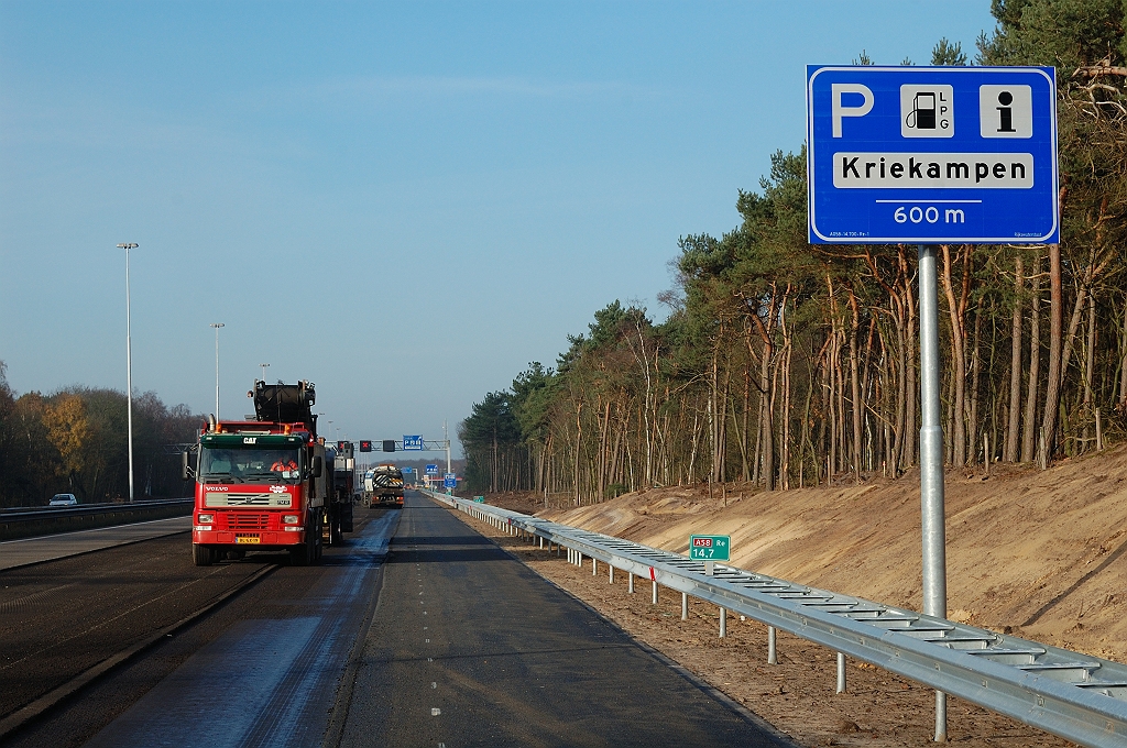 20101120-105636.jpg - Informatie op het nieuwe 600 meter bord is dezelfde als op het oude. De rechtsafpijl is echter verdwenen. Verder details zoals de afstand onder de streep in plaats van in een kader, en het verdwijnen van het groene "schaduw" pompsymbooltje dat LPG symboliseerde. In de voormalige vluchtstrook zien we trouwens weer diepergaand freeswerk dan voor het verwijderen van de ZOAB deklaag noodzakelijk is. Wellicht was de bestaande asfaltconstructie niet geschikt voor een voortdurende verkeersbelasting.