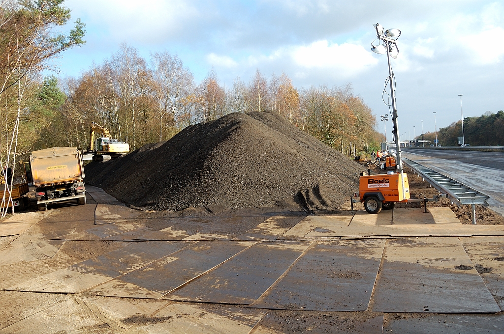 20101120-122916.jpg - Kennelijk wordt het afgefreesde oude ZOAB eerst verzameld in de oude aansluiting, en dan overgeladen voor transport naar de recycling. Een voor de hand liggende lekenvraag is dan ook waarom de vrachtwagens die het affreesel initieel opvingen, niet meteen doorreden naar de recycling locatie.