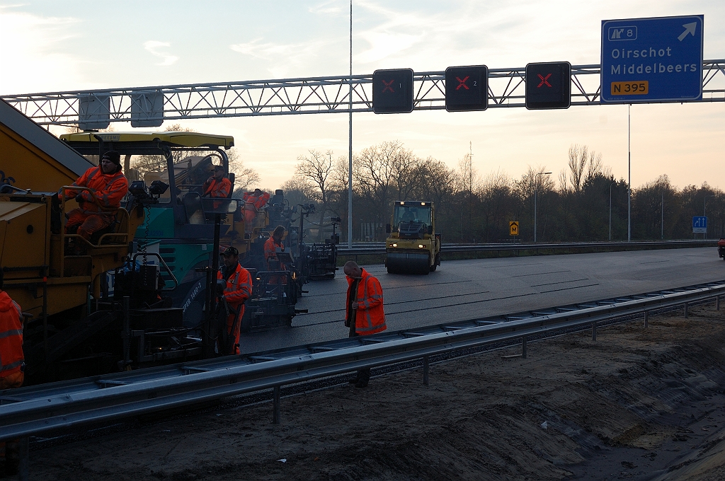 20101121-153008.jpg - Aanbrengen tweede, fijnkorrelige, ZOAB deklaag op de zondagmiddag. Goed te zien hier dat de paralelle formatie van spreiders van zichzelf geen vlakke toplaag achterlaat. Er moet dan ook flink radiaal en diagonaal gewalst worden.