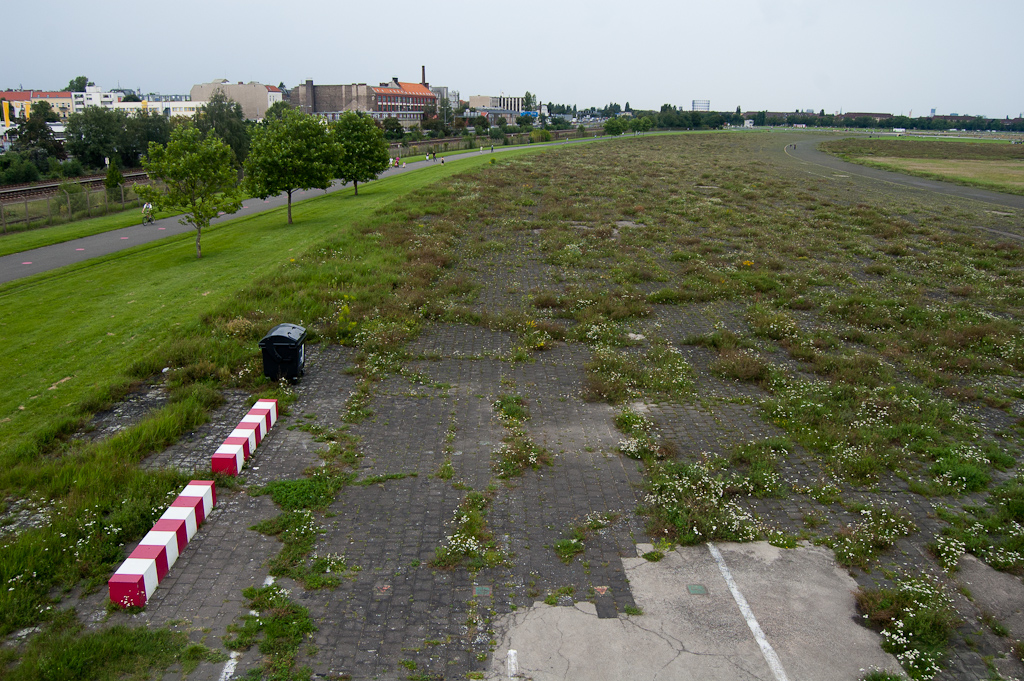 20110814-153955.jpg - Uitzicht vanaf het torentje uit de vorige foto langs de zuidelijke grens van het vliegveld. De thans overwoekerde verharding vormt een brede gekromde baan, maar lijkt geen nut te hebben gehad voor het bereiken van de startbanen door vliegtuigen. Wat was het dan wel...