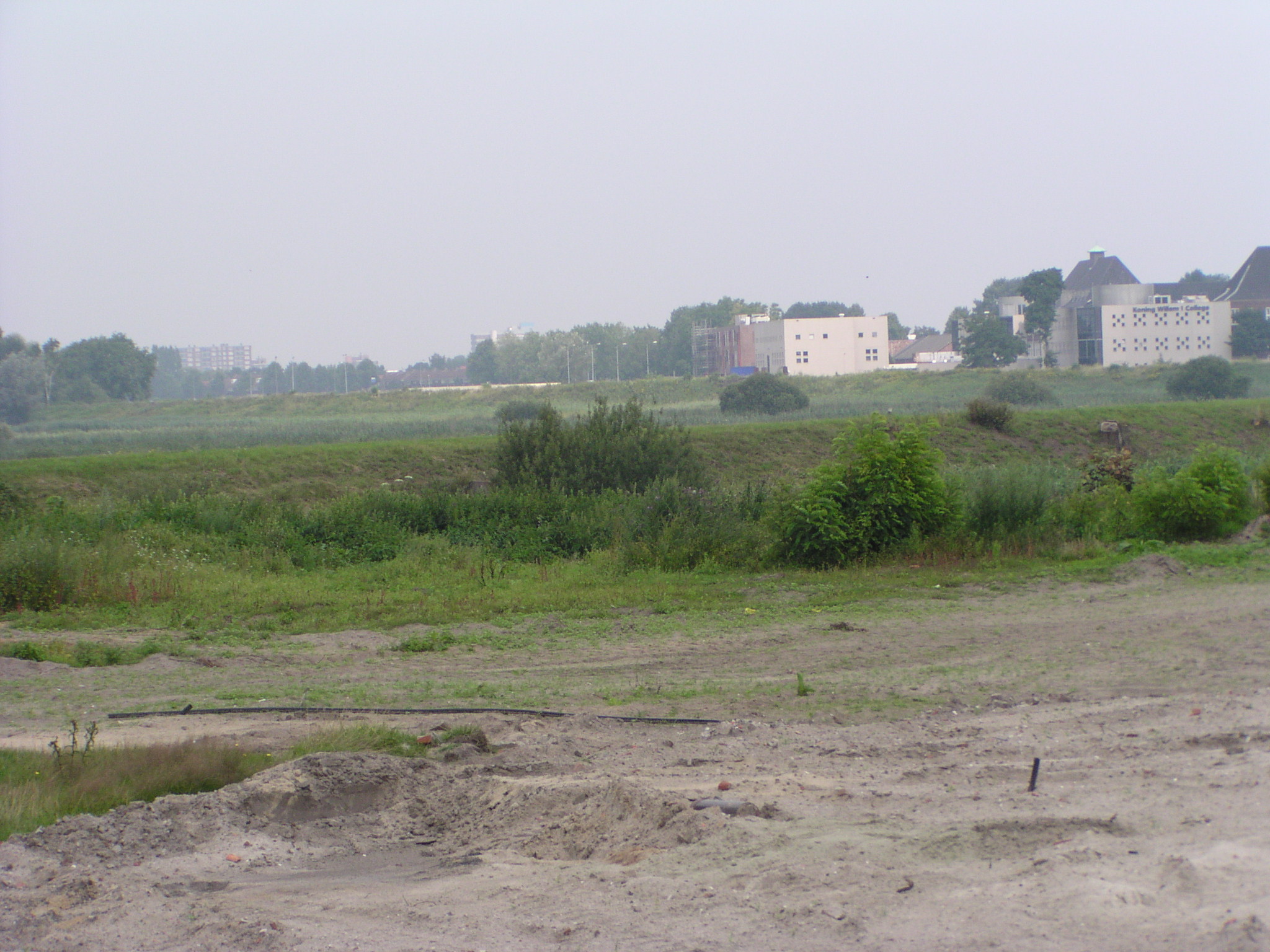 p7300016.jpg - Voorlopig einde van het zandlichaam voor de Gementweg tussen spoorlijn en het afwateringskanaal 's Hertogenbosch-Drongelen. In de verte is een streepje zand zichtbaar waar de weg naar toe moet. Niet recht door het natuurgebiedje de Gement, maar erlangs, tussen kanaal en spoorlijn. Vervolgens via een nieuwe brug over het kanaal naar de zuidrand van de voormalige Koning Willem I kazerne (thans een school), waar de fotograaf zijn militaire dienstplicht nog vervuld heeft.