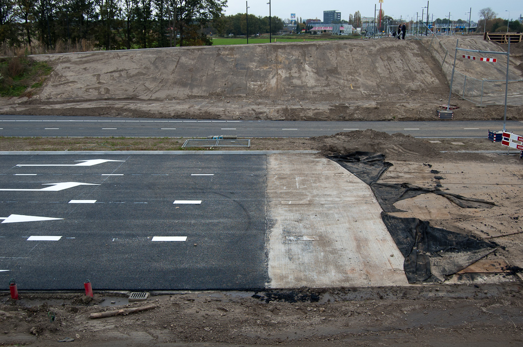 20111030-140515.jpg - Voor het aanbrengen van de deklaag op de toeleidende wegen is de bescherming van de betonnen rijbanen in de Hovenring kruising plaatselijk verwijderd. Je kunt de markeringen op het beton, die 10 weken geleden al zijn aangebracht, nog net herkennen.