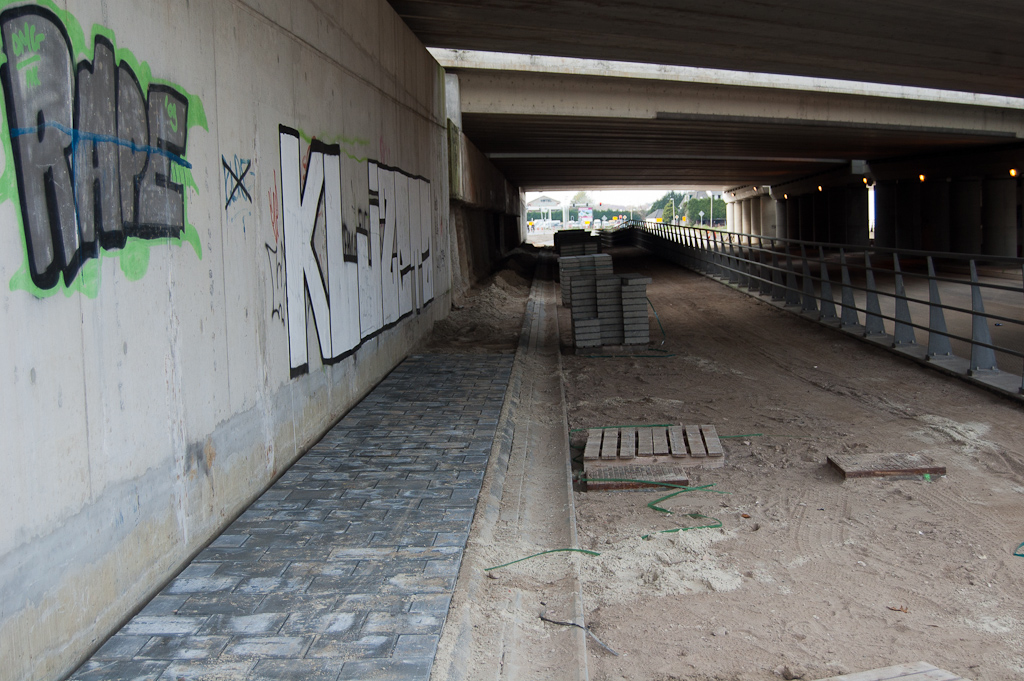 20111030-152900.jpg - Onder het viaduct is de teruglegging van het versmalde voetpad in uitvoering, ten behoeve van de verbreding van het fietspad zodat het in twee richtingen kan worden bereden.  week 201139 